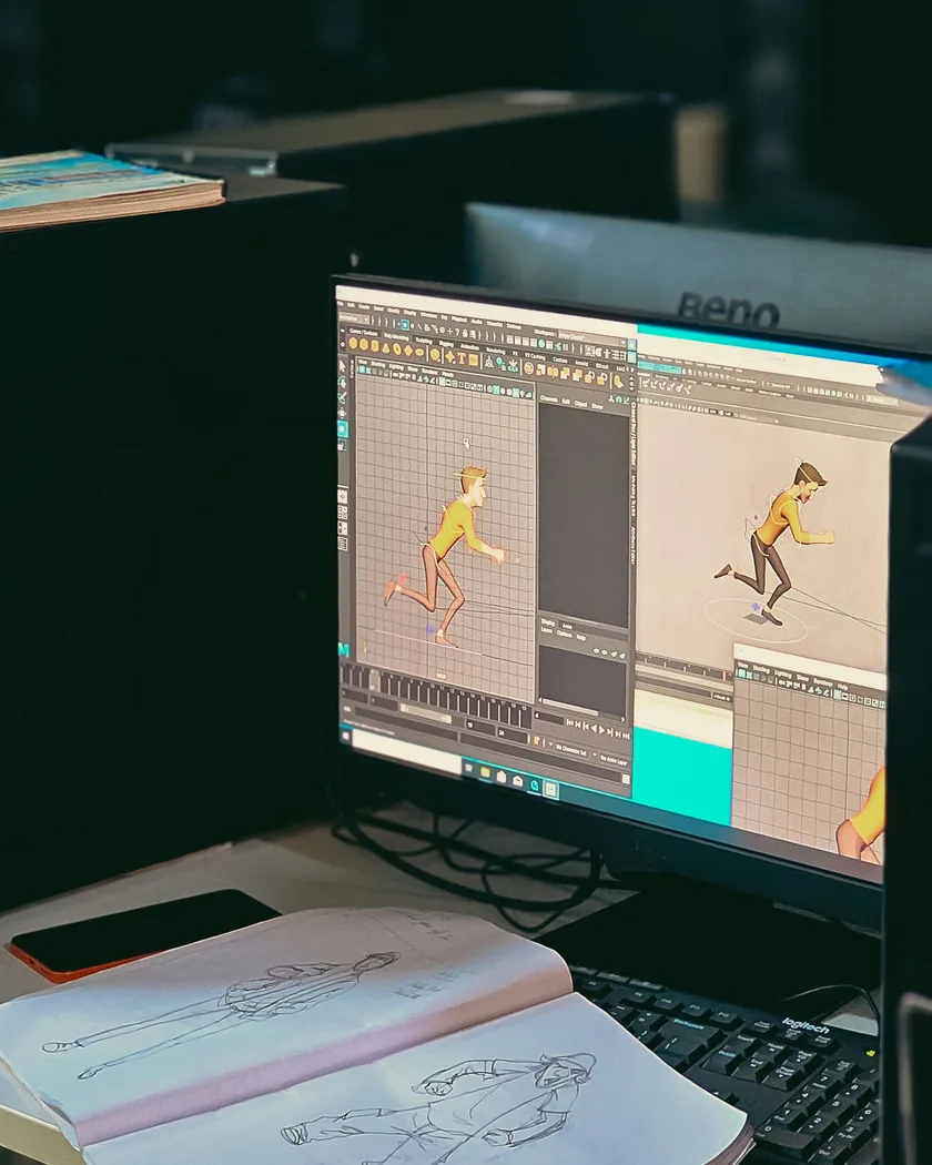 Mesa de trabajo con bocetos de personajes en papel y un diseño digital abierto en la pantalla
